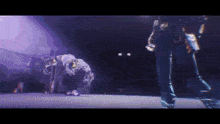 a group of people are dancing on a stage with purple lights behind them