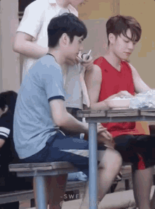 a group of young men are sitting at a table eating