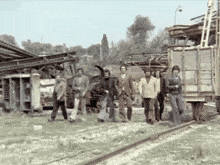 a black and white photo of a group of men standing on a train track