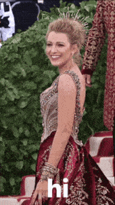 a woman wearing a red dress and a crown is smiling and says hi