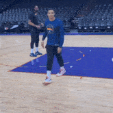 a man walking on a basketball court wearing a denver nuggets shirt