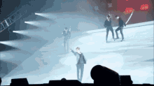 a group of people are standing on a stage in front of a spotlight