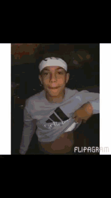 a young man wearing a headband and an adidas sweatshirt shows off his stomach