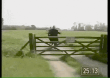 a man is jumping over a fence in a field with a time of 25.13