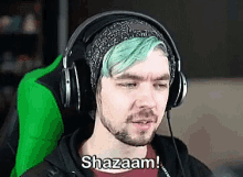 a man with green hair and a beard wearing headphones and a beanie is sitting in a green chair .