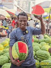 a man in a blue shirt with the letter g on it holds up a watermelon