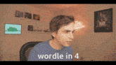a man in a blue shirt is sitting at a desk with the words wordle in 4 above him