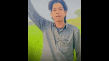 a young man in a blue shirt is standing in a green field .