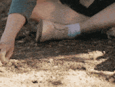 a person is kneeling on the ground and picking up rocks with their hand
