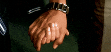 a man and a woman are holding hands and the man is wearing a watch