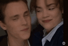 a man and a woman are smiling for a picture and looking at the camera .