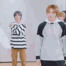 a group of young men are standing next to each other in a room . one of the men is wearing a striped shirt .