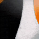 a black , white and orange balloon is floating in the air on a black background .