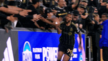 a soccer player celebrates a goal in front of a banner that says power
