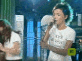 a woman singing into a microphone while wearing a t-shirt that says ' хуй войне '