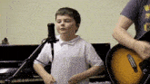 a boy is singing into a microphone while a man plays a guitar