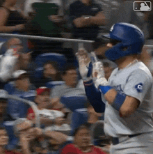 a baseball player wearing a dodgers uniform is standing in front of a crowd of people .