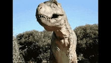 a statue of a dinosaur is standing in front of some trees