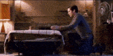 a man is kneeling down in front of a bed in a bedroom .