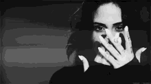 a woman with white nails is covering her face with her hands .