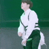 a man in a white shirt and black pants is holding a microphone while dancing on a stage .
