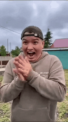 a man wearing a hat and a sweatshirt that says be a winner on it is clapping his hands .