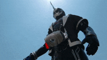 a statue of a superhero with a helmet on stands in the sun