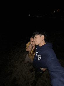 a man wearing a blue sweatshirt with the letter s on it hugs a woman