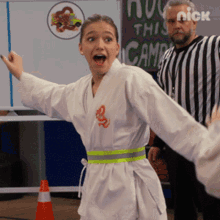 a girl in a karate uniform is standing in front of a sign that says nick