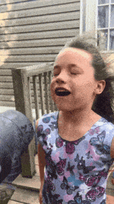a little girl wearing a butterfly print shirt is making a funny face