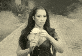 a woman in a black dress holds a white rose in her hand
