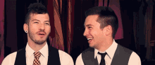 two men are standing next to each other and laughing .