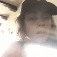 a woman wearing a baseball cap is taking a selfie while smoking a cigarette .