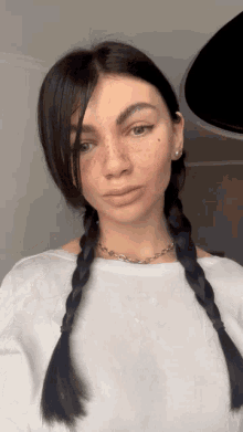 a woman with braids and freckles on her face is wearing a white shirt