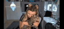 a woman is holding a cat in front of a screen that says ' twitch ' on it