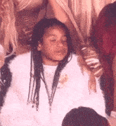 a young girl with braids is sitting in a crowd of people .