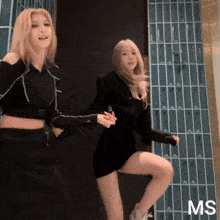 two women are dancing in front of a wall that has the letter ms on it