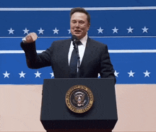 a man in a suit and tie stands at a podium with the seal of the president of the united states on it