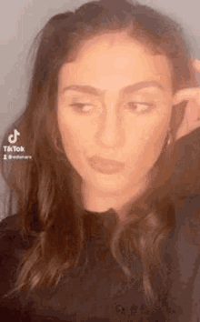 a woman in a black shirt is making a funny face while holding her ear .