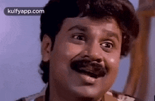 a man with a mustache is making a funny face and smiling .