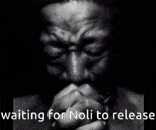 a black and white photo of a man praying with the words waiting for noli to release above him
