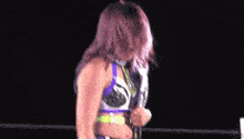 a woman is standing in a wrestling ring holding a purple and green belt .