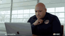 a man sitting in front of an apple laptop with a chicago fire logo on his jacket