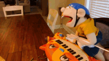 a puppet wearing a blue helmet sits on a piano