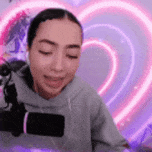 a woman is sitting in front of a microphone with her eyes closed and a heart in the background .