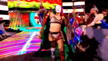 a woman in a mask is walking on a stage in front of a crowd of people .