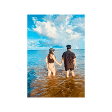a man and a woman holding hands in the ocean