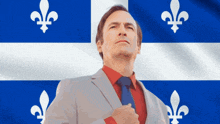 a man in a suit and tie stands in front of a flag