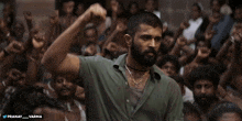 a man stands in front of a crowd with his fist in the air and the caption pranay_varma