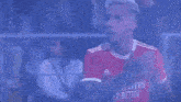 a soccer player in a red jersey is giving a thumbs up during a game .